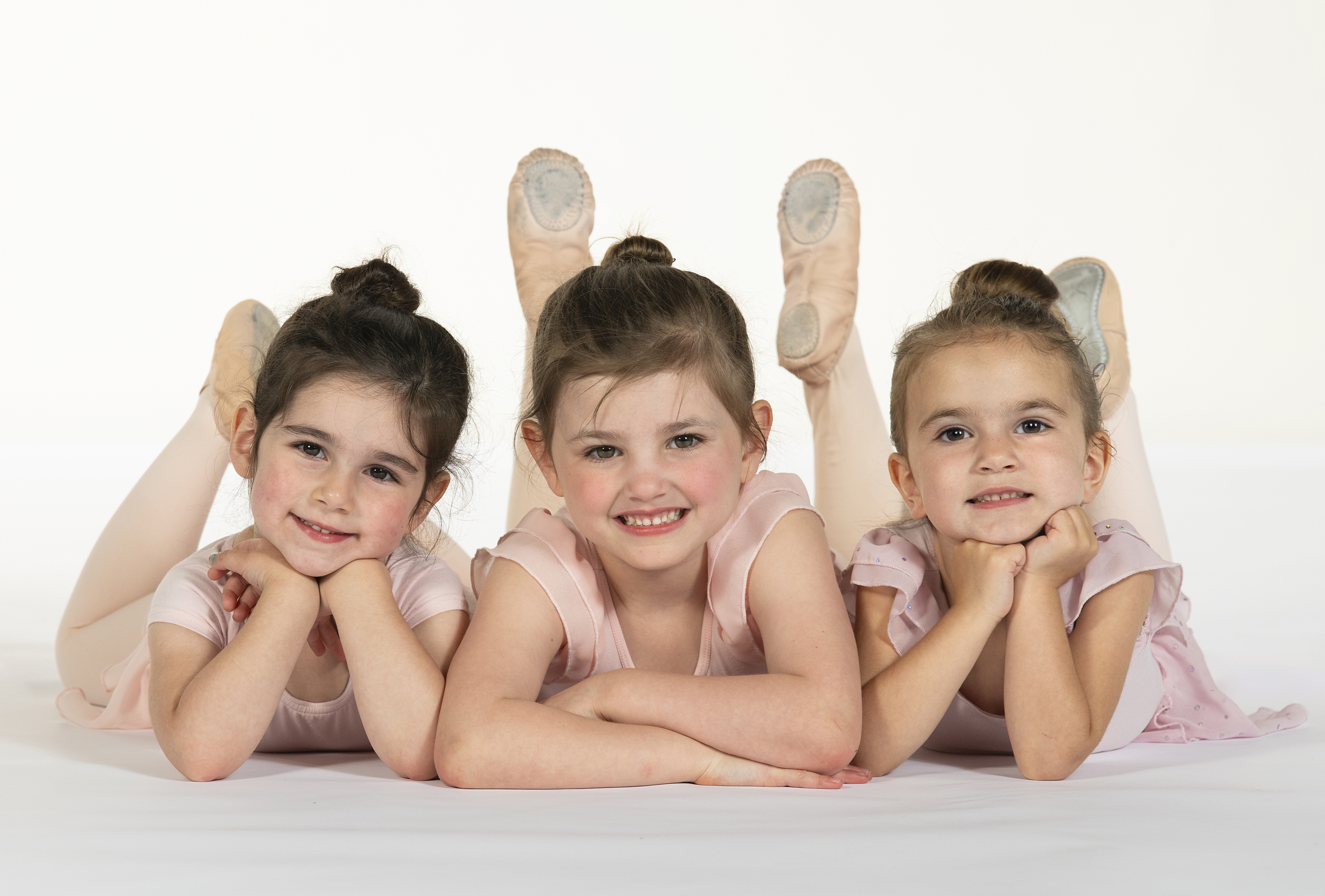 three preschoolers on their tummies smiling